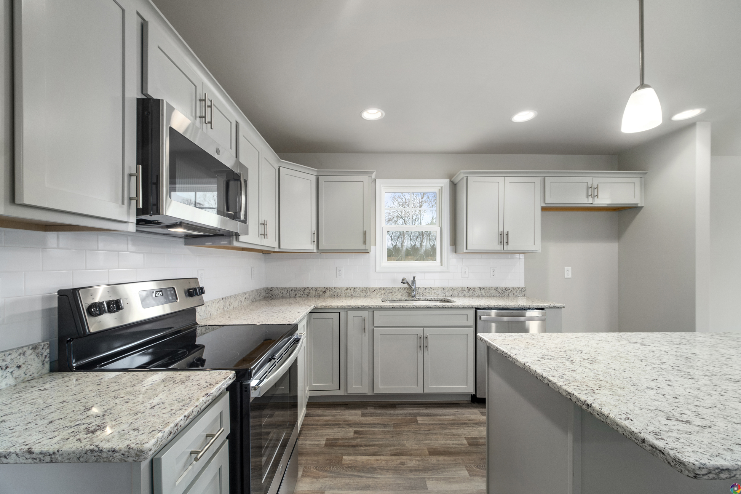Modern kitchen interior with gray cabinets, stainless steel appliances, and granite countertops.
