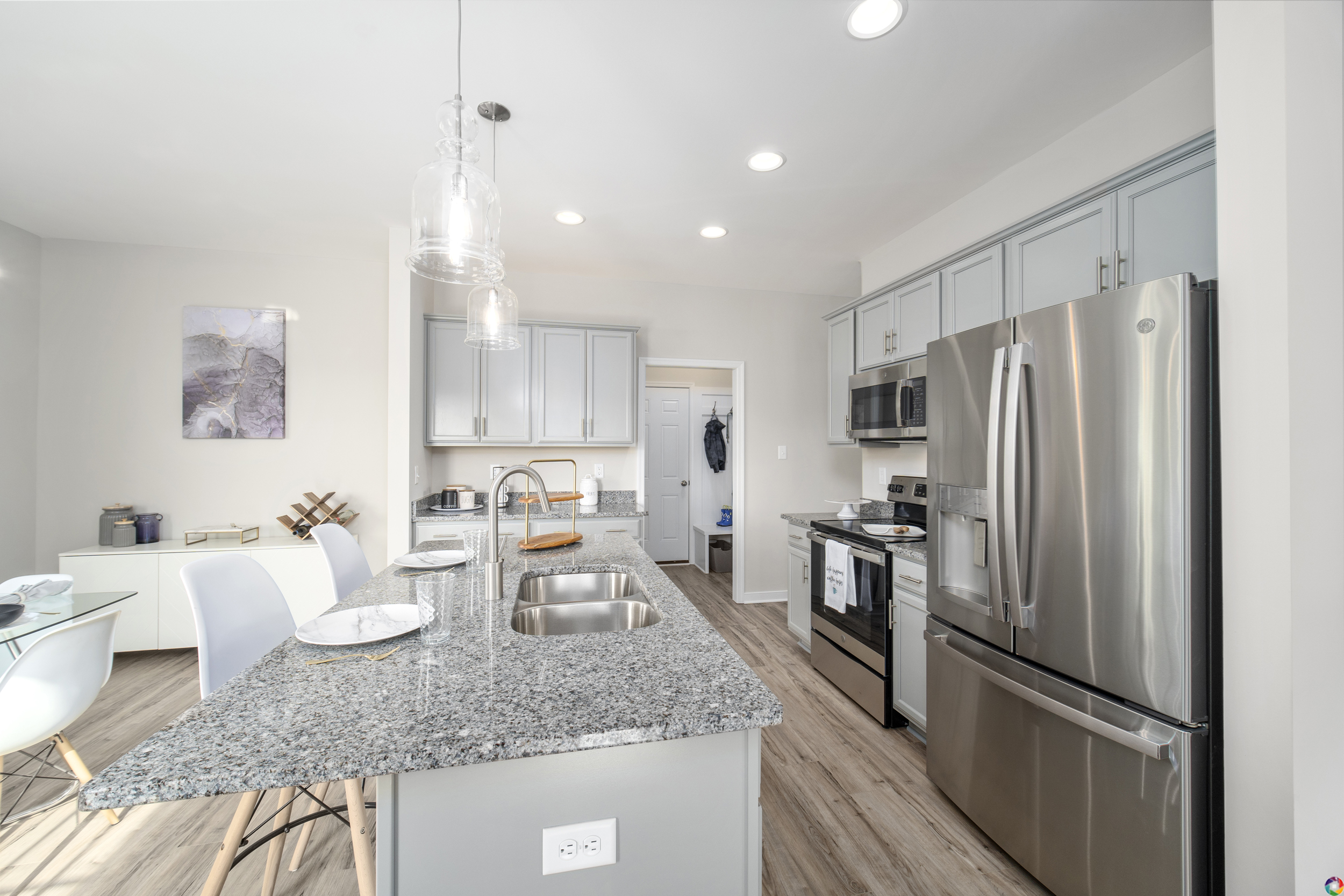 Modern kitchen interior with stainless steel appliances, granite countertops, and pendant lights.