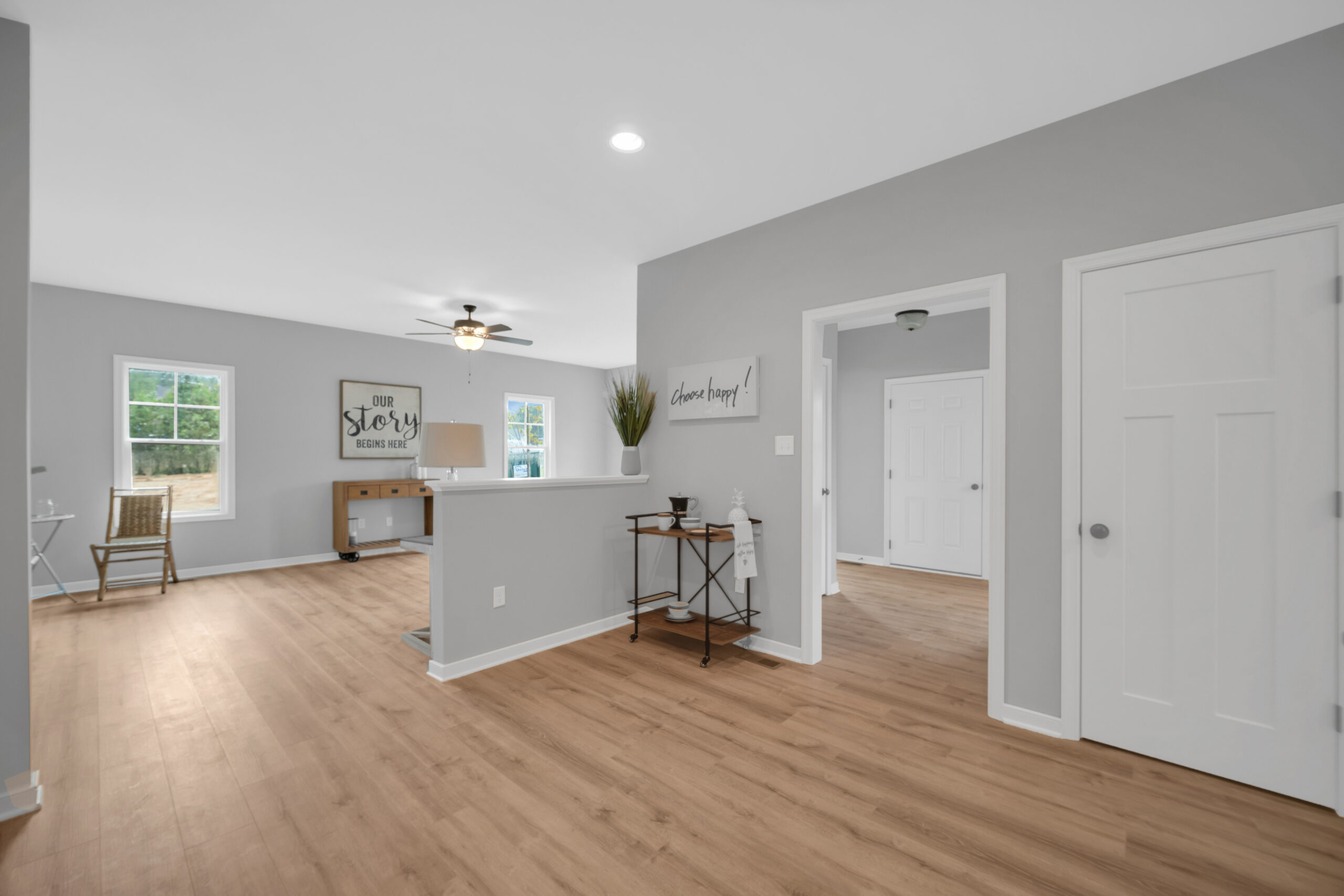 Modern living room and adjoining dining area with light grey walls, wooden flooring, white doors, and minimalistic decor.
