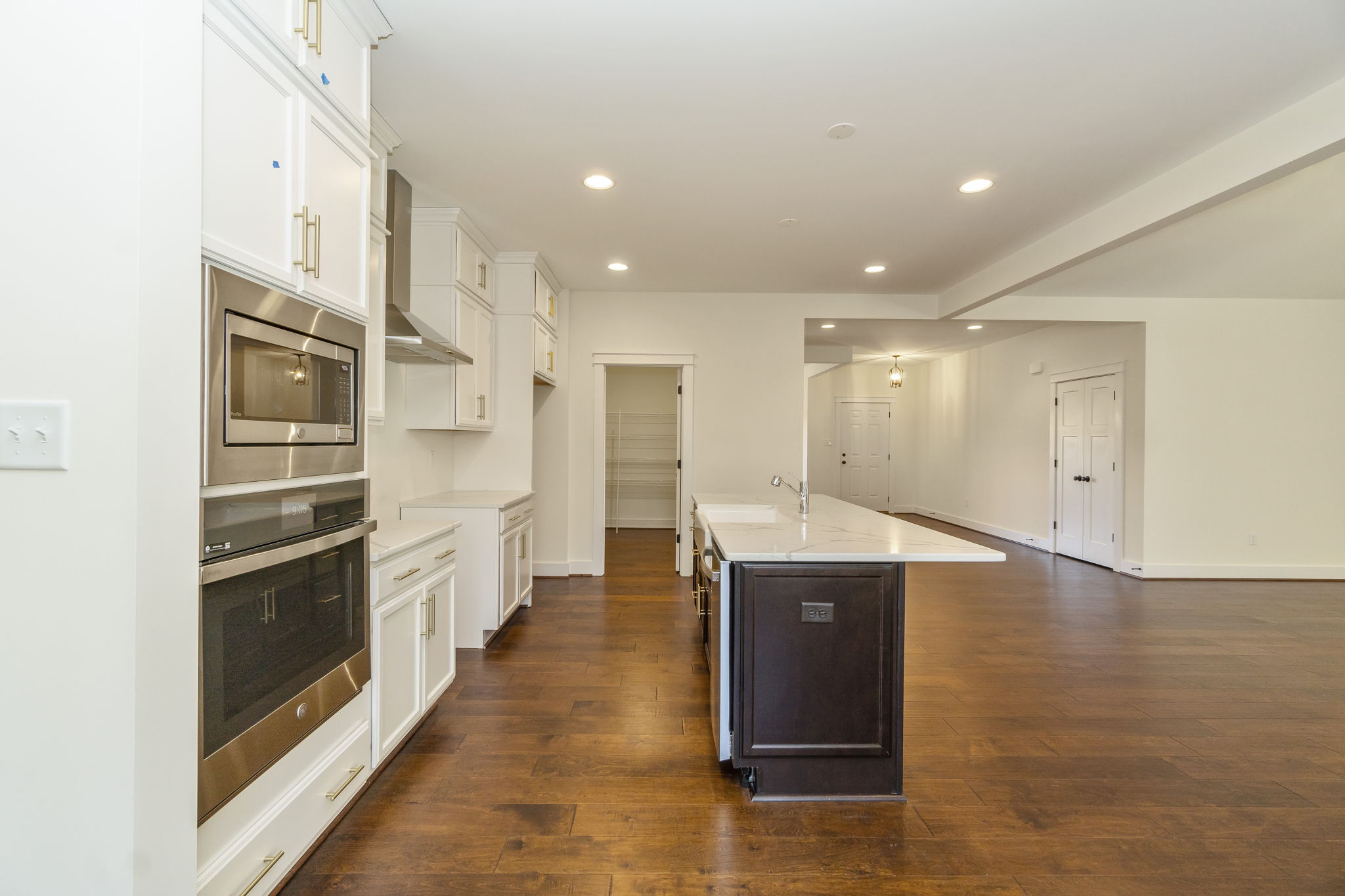 Modern kitchen with white cabinetry, stainless steel appliances, a central island, and hardwood floors.