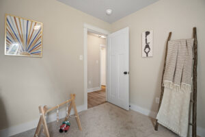 The minimalist playroom at Haley Meadows features a wooden toy, a decorative ladder, and framed wall art. The door stands slightly ajar, inviting both light and imagination inside.