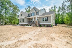 Two-story house with gray siding and stone accents in new homes in Richmond, surrounded by a tree-filled yard.