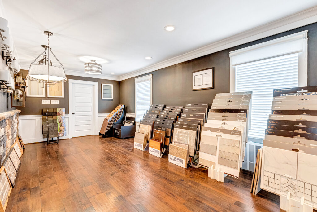 Design center showroom with wood flooring and tile samples displayed on racks along the walls.