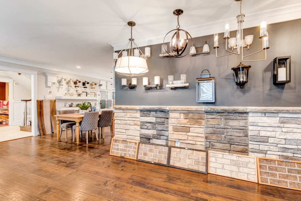 Spacious room with wooden floors, dining area, stone accent wall, and various light fixtures on display at the Design Center.