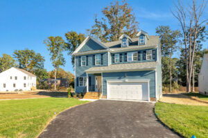 Blue two-story house with attached garage, featuring a driveway and green lawn.