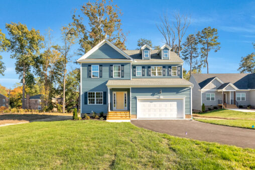Two-story blue house with white trim and garage on sunny, grassy
