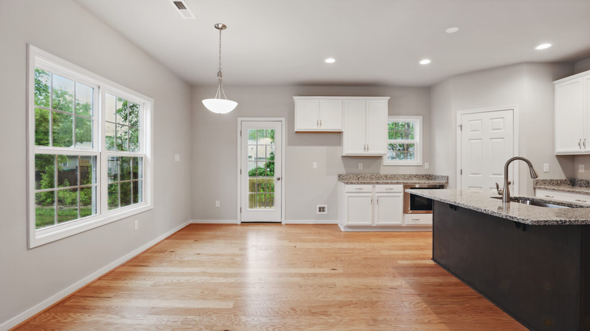Modern Bethany kitchen with white cabinets, granite countertops, wood floors, and large Somerset Hill windows.