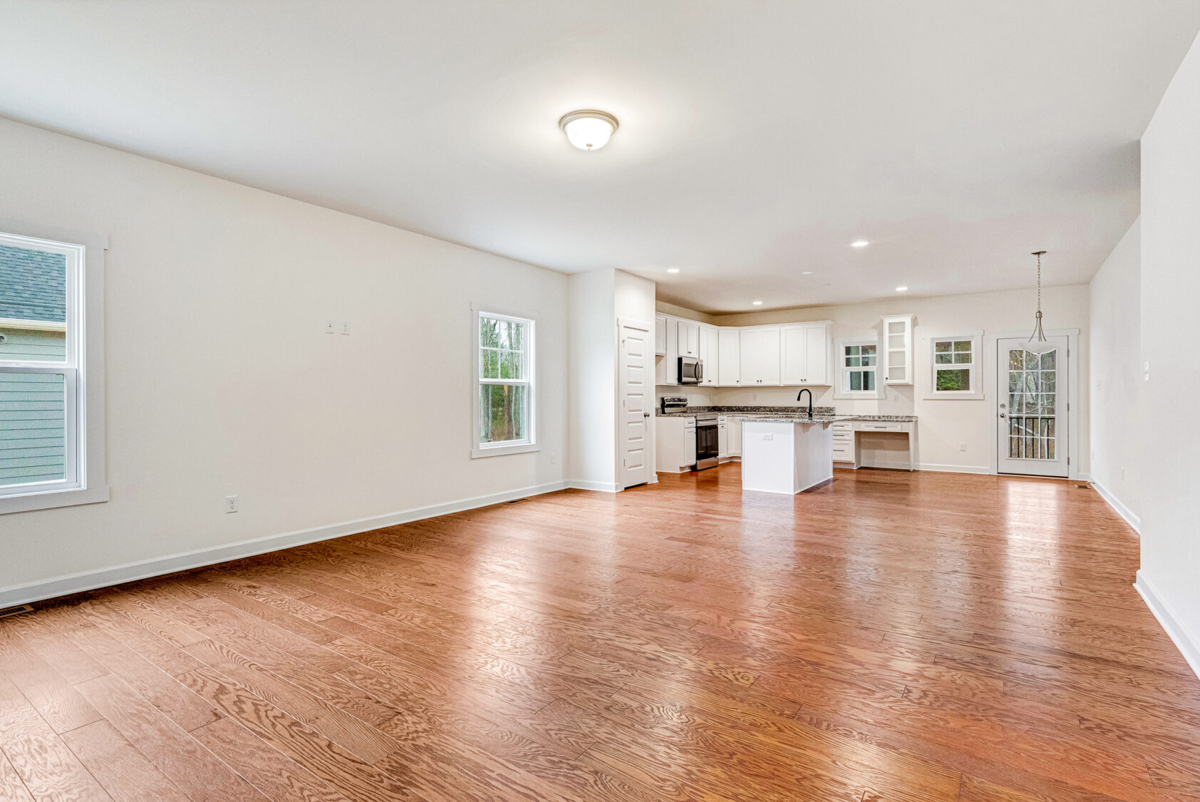 Bright, open-concept living area with hardwood floors and a modern white kitchen at Somerset Hill.
