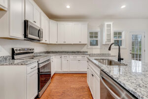 Modern Somerset Hill kitchen with white cabinets, granite countertops, stainless steel appliances, and wood flooring.