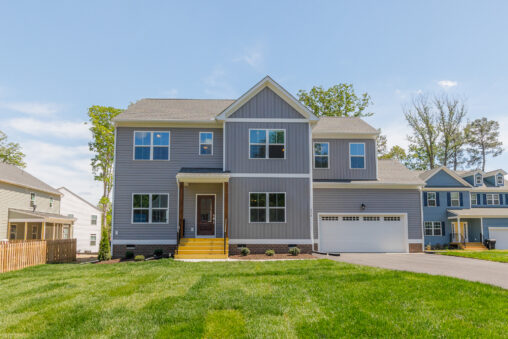 Two-story gray suburban house in Poplar Village with a front porch, garage, driveway, and well-kept green lawn.