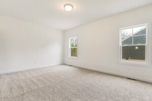 Empty room in Somerset Hill with beige carpet, white walls, ceiling light, and two windows framing the view outside.