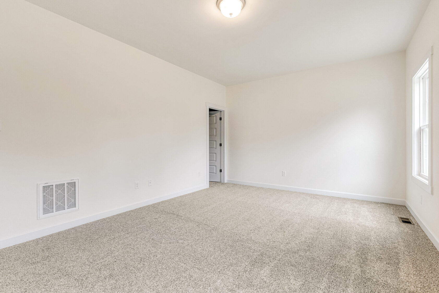 Empty room with beige carpet and white walls in Somerset Hill, featuring a window and an open door.