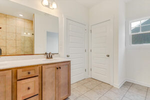 Bathroom with wooden vanity, large mirror, tiled floor, and a window on the right at Somerset Hill.