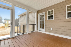 Covered porch at Somerset Hill features a brown wooden floor, beige siding, white trim, and a glass door to the outside.