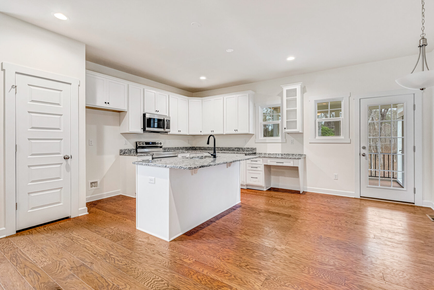 Bright Somerset Hill kitchen with white cabinets, granite counters, hardwood floors, and stainless steel appliances.