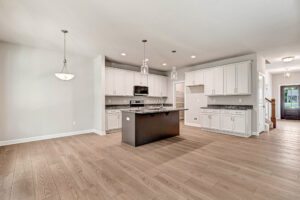 Modern kitchen in Somerset Hill Lot 5 with white cabinets, a dark central island, and wood-look flooring.