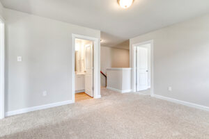 Empty carpeted hallway at Lot 5 with two open doorways, one showing a bathroom vanity.